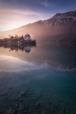 Tranquil lake with boats on pier and resort against mountains