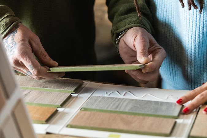 Anonymous woman choosing sample with carpenter in workshop