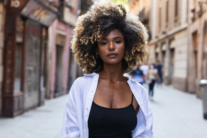 Gorgeous woman with curly hair standing on street
