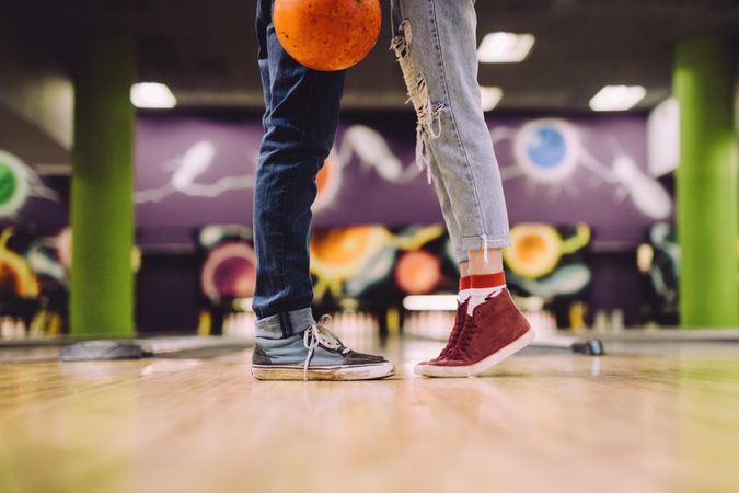 Focus on legs of man and woman with bowling ball