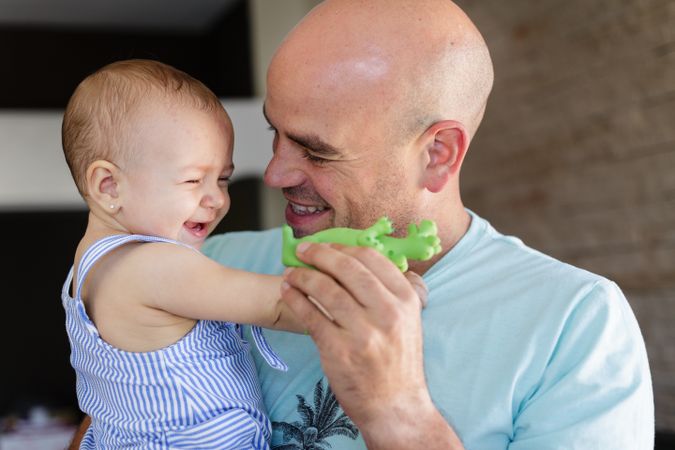 Cheerful father playing with baby at home