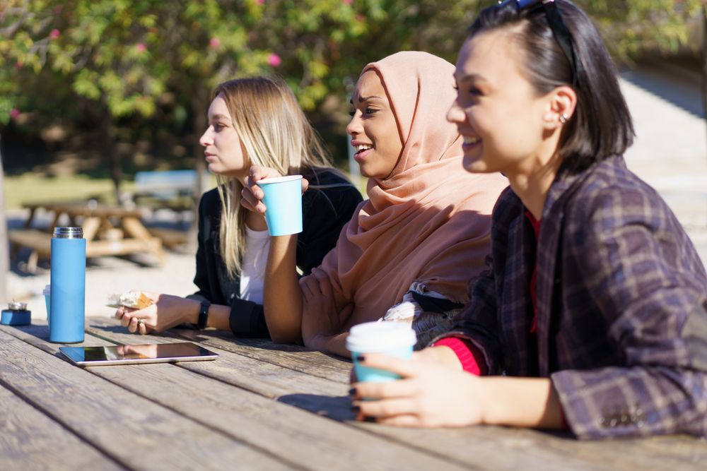 Smiling women sitting outside in park looking ahead