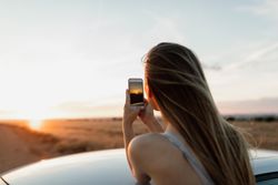 Back view of young female taking a sunset photgraph