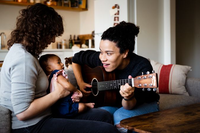 Woman playing acoustic guitar for baby and partner