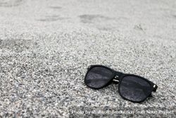 Sunglasses sitting on grey sandy pebbles 5l99Y4