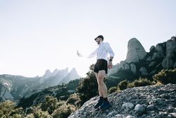 Man in athletic gear taking picture with phone out on nature