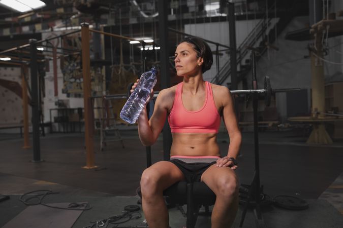 Smiling woman with bottle of water in gym