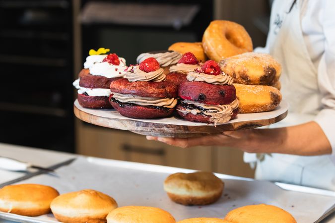 Crop woman with Berliners on tray in bakery