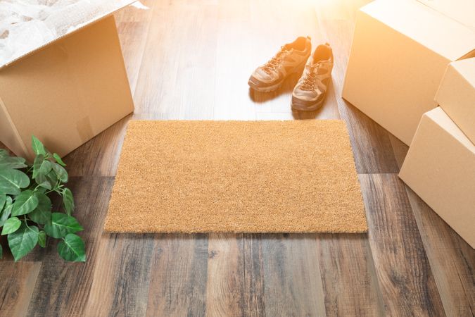 Blank Welcome Mat, Moving Boxes, Shoes and Plant on Hard Wood Floors