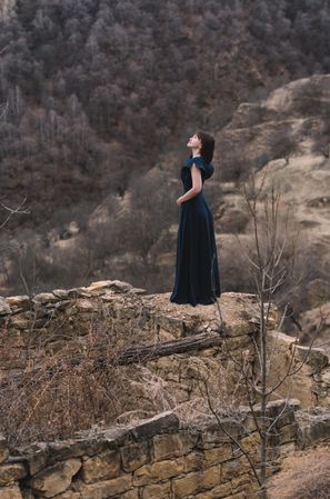 Woman in long blue dress standing in natural landscape in Hamsutl, Dagestan