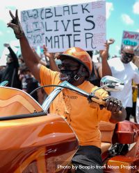 Man in orange shirt and helmet riding orange motorcycle at Black Lives matter protest 48n3Z0