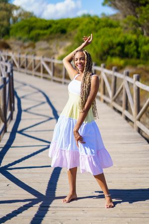 Smiling female looking at camera and walking on a pedestrian walkway in colorful dress