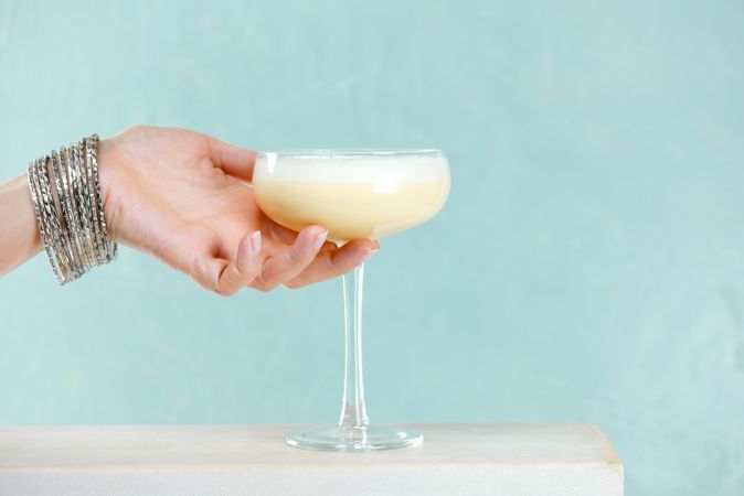 Woman reaching for cocktail glass of eggnog