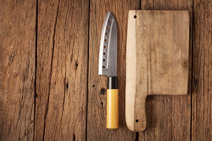 Chef knife and cutting board on rustic wooden table.
