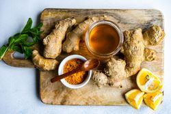Top view of raw ginger, lemon, turmeric & honey on board