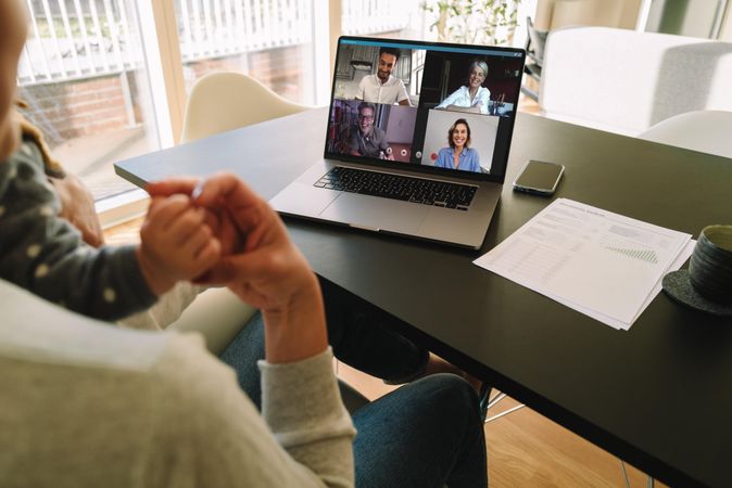 Woman with her child having video call with coworkers while working from home
