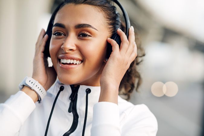 Smiling woman with both hands on headphones