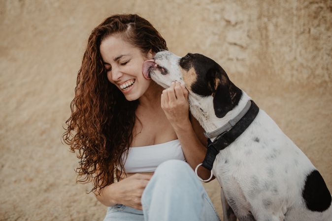 Dog licking face of cheerful woman