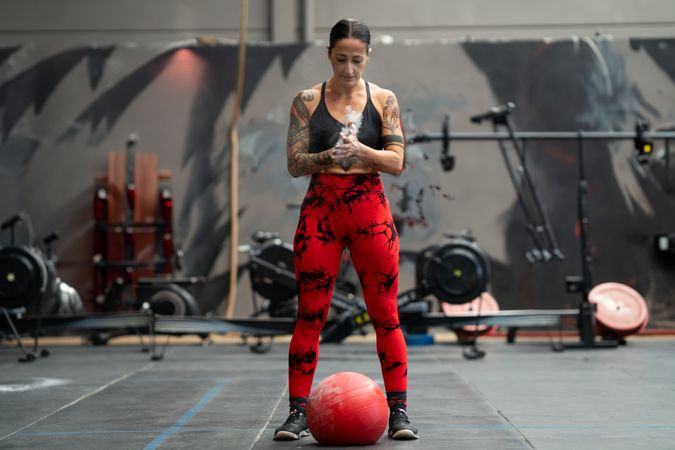 Woman dusting hands before weightlifting with medicine ball