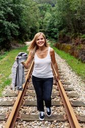 Woman walking along railway though greenery part of road