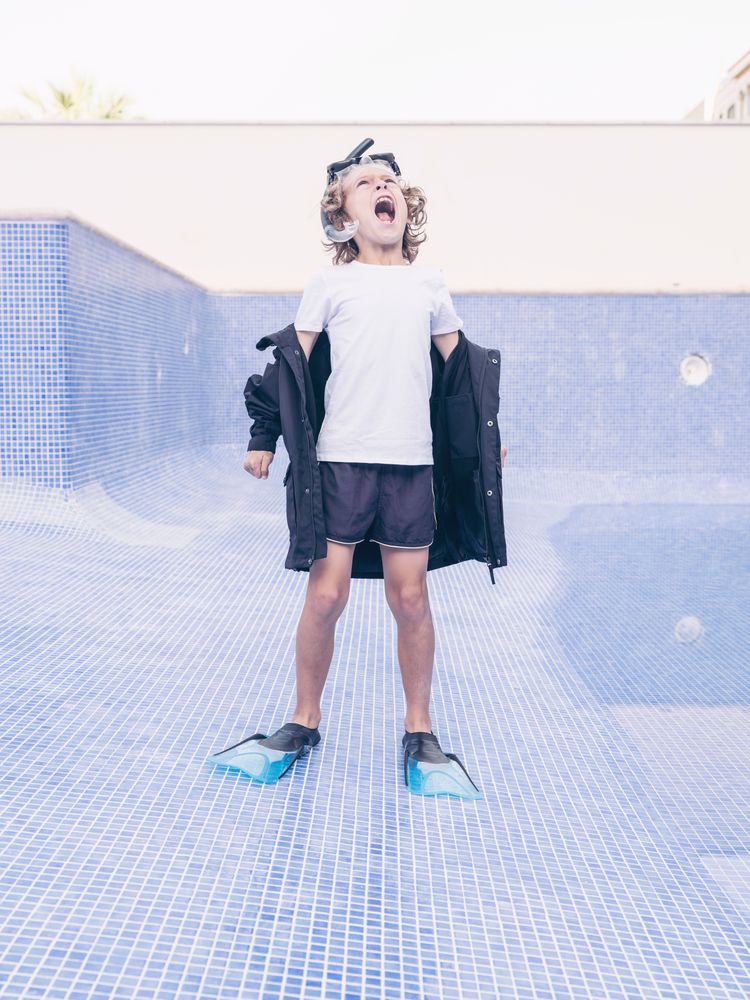 Angry boy in flippers and mask in empty pool