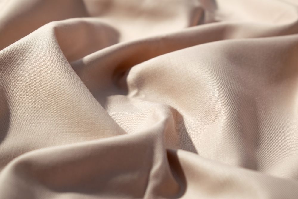 Close up silk shiny light brown fabric background texture.