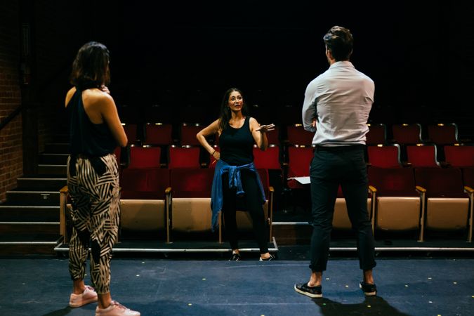 Female director giving feedback on a scene to two actors in a theater