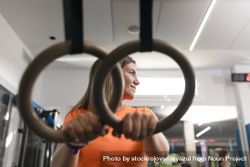 Portrait of a female trainee resting her hands on the rings at the gym 4Azz2W
