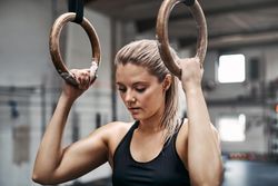 Healthy and serious woman getting focused before workout on gymnastic rings