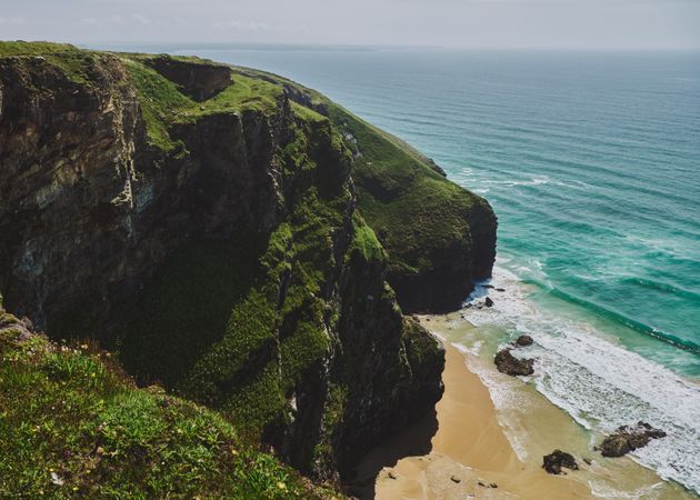 Beautiful view from top of a green cliff looking down at the beach