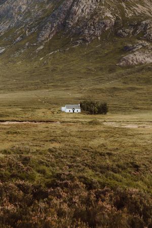 Lonely house in field by mountain