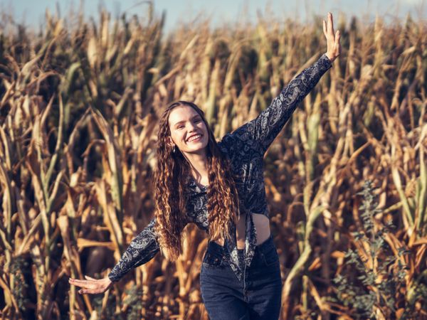 A Joyful Young Woman Dancing Happily in a Beautiful and Expansive Cornfield on a Sunny Day