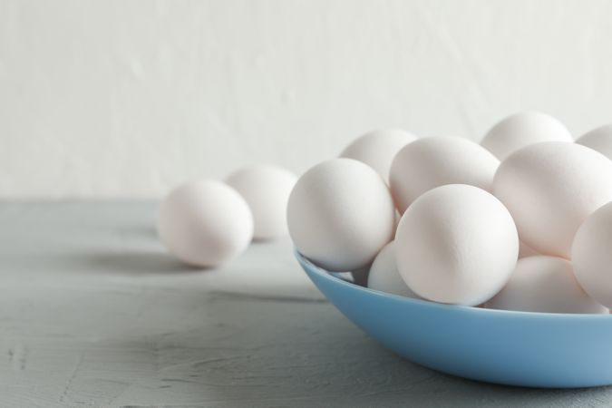 chicken eggs in plate on grey table against light background, space for text