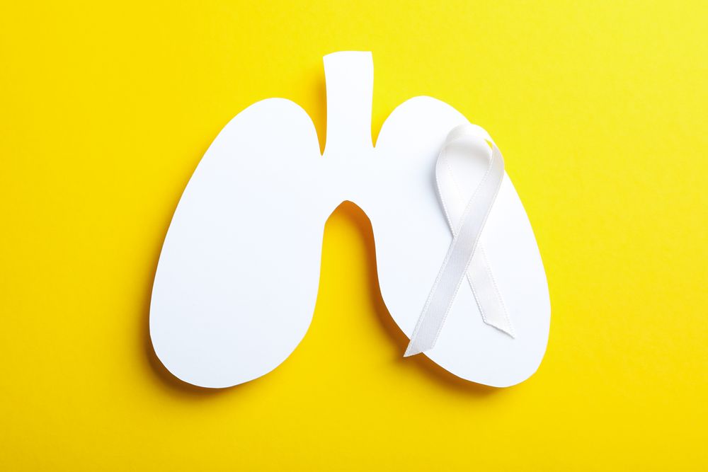 Lung shape cut out of paper with ribbon on yellow background