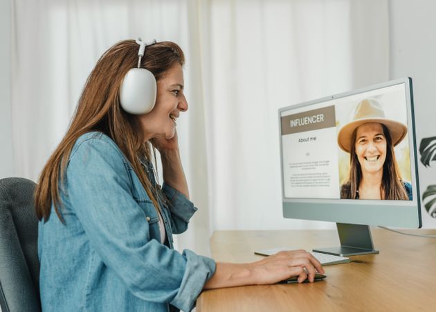 Woman in headphones using computer at home