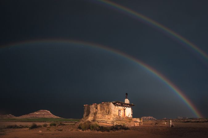 Lonely house in desert and rainbow in sky