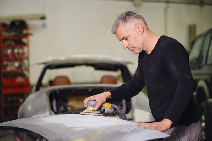 Mechanic grinding paint from car detail