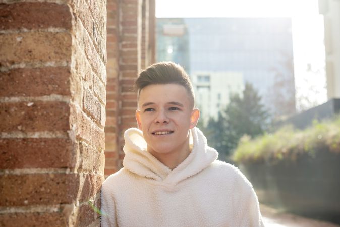 Portrait of smiling young man leaning against brick wall