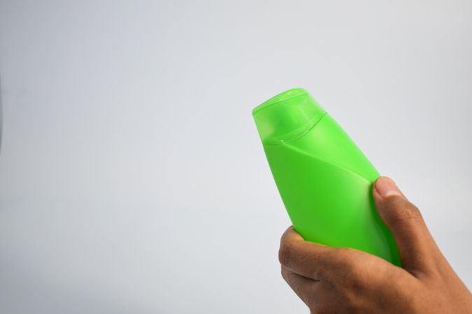 Hand holding green shampoo bottle