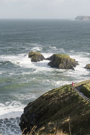 Person walking on country road between sea and field