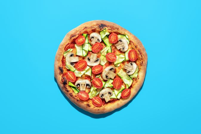 Vegan pizza above view, isolated on a blue background