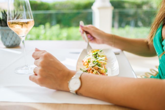 Crop woman eating salad on terrace of restaurant