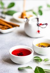 Red tea in small cup with tea pot in background