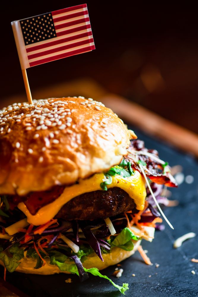 Close up of bacon cheeseburger topped with flag