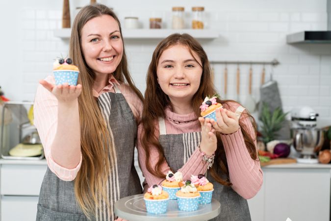 Mother and daughter with decorated cupcakes at home