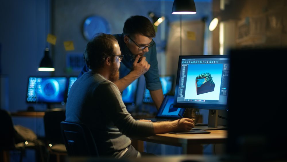 Two Male Game Developers Discuss Game Level Drawing, One Uses Graphic Tablet.
