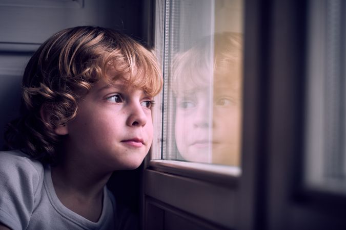 Dreamy cute kid looking out window