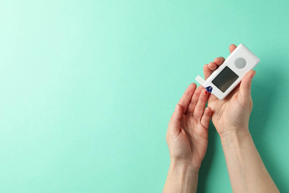 Female checking blood sugar level on mint background