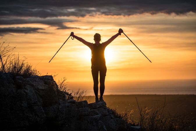 Silhouette of person with walking sticks in sunset