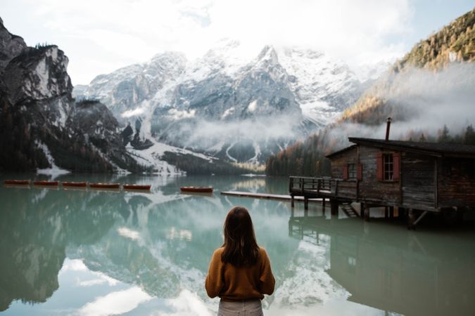 Resting woman in casual wear delighting in views near lake and mountains